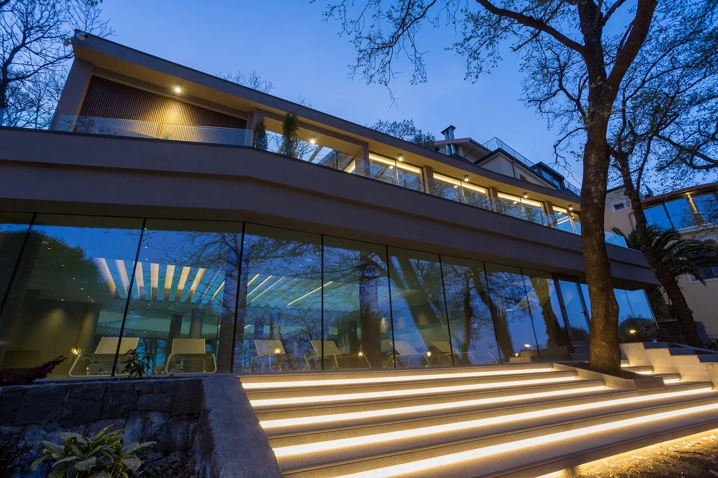 Edificio moderno dell'hotel con grandi vetrate e scalinata illuminata al crepuscolo