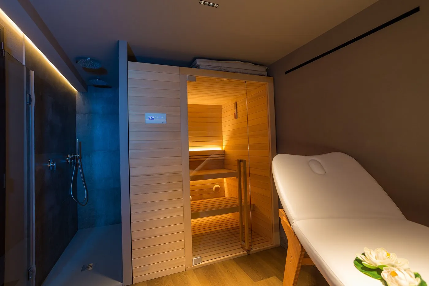 Area spa privata con sauna in legno, doccia e lettino da massaggio