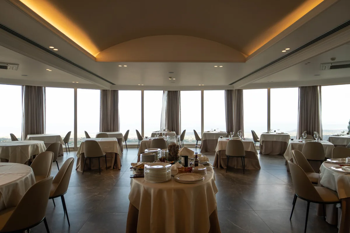 Sala ristorante panoramica con tavoli apparecchiati e ampie vetrate con vista
