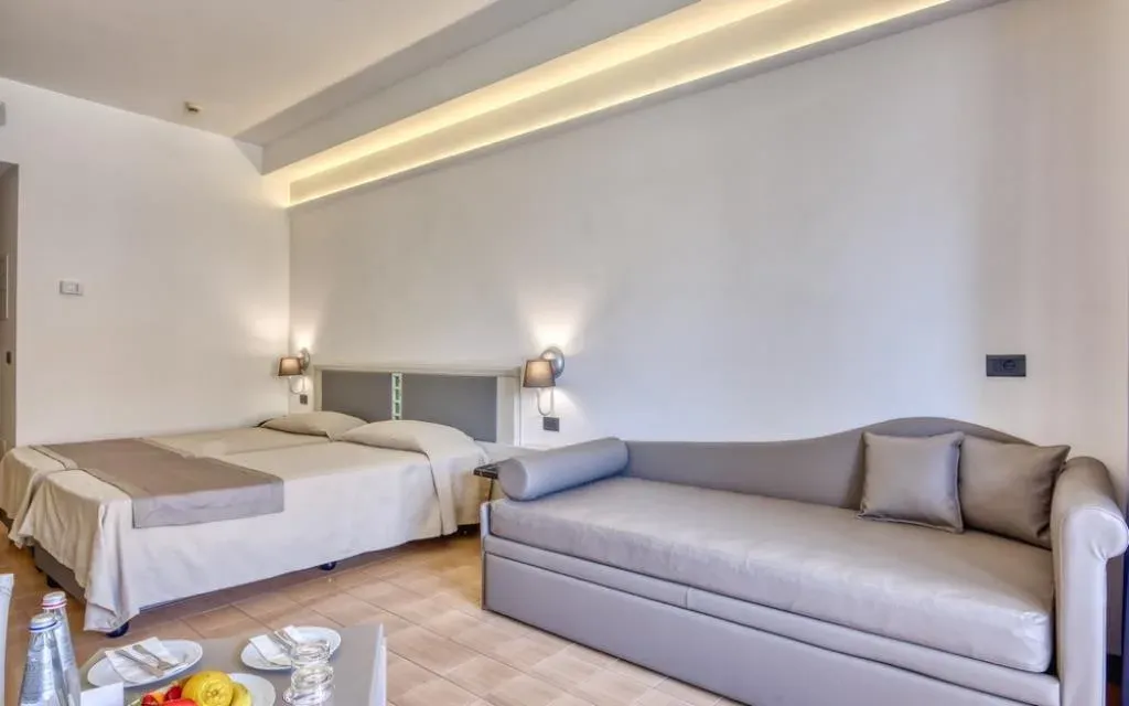 Camera moderna con letto matrimoniale e divano in tonalità chiare