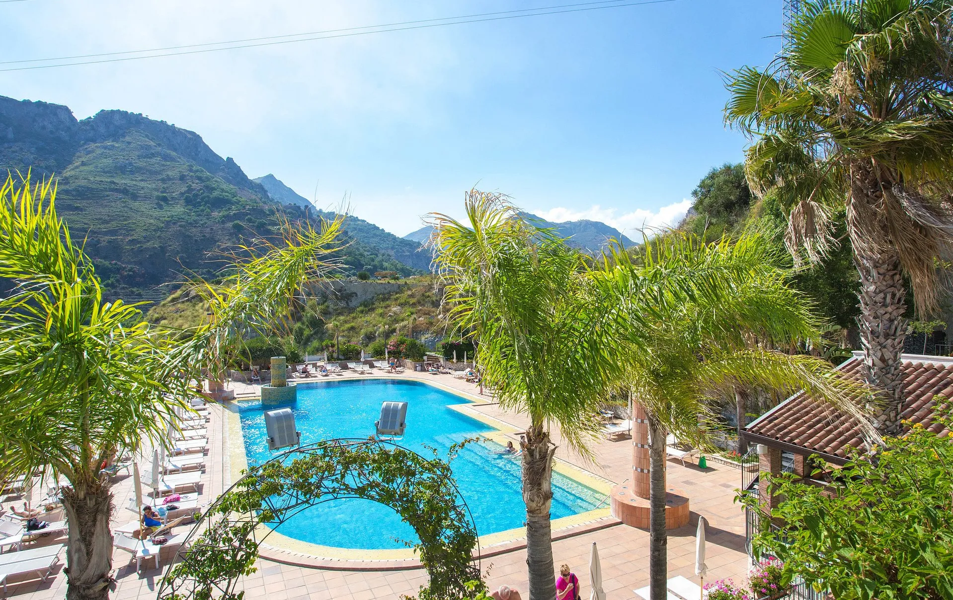 Vista dall'alto della piscina dell'hotel circondata da palme e montagne