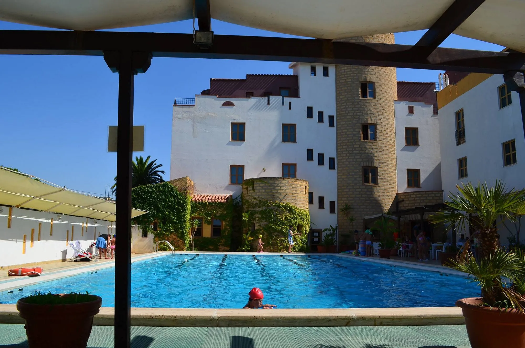 Piscina esterna con ospiti in acqua e vista sulla torre in pietra dell'hotel