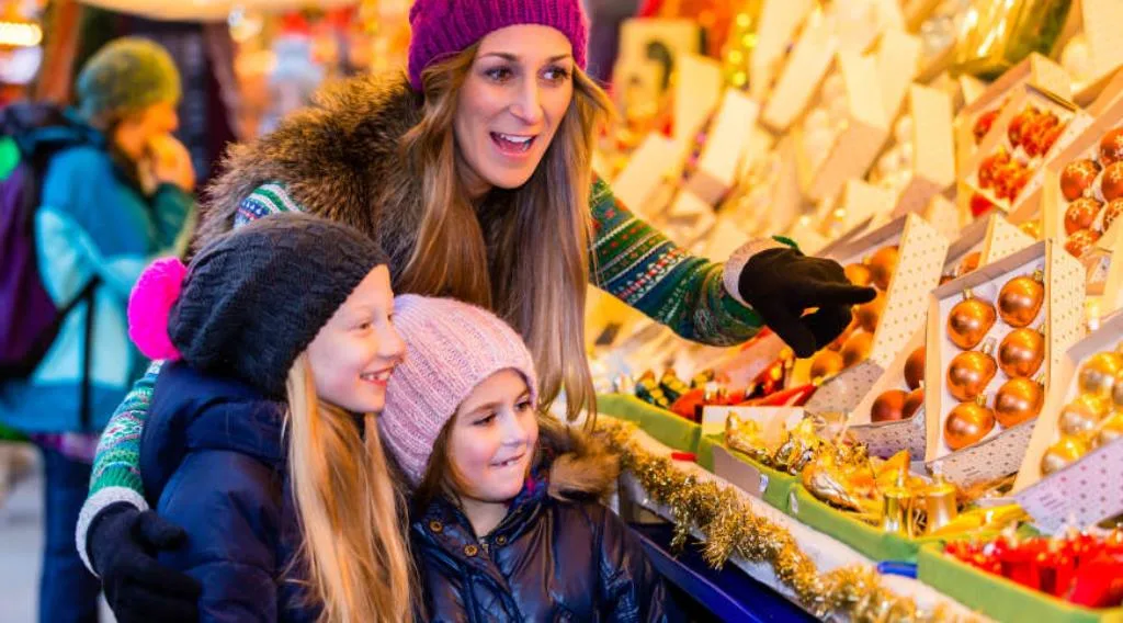 Famiglia ai mercatini di Natale tra decorazioni e addobbi dorati