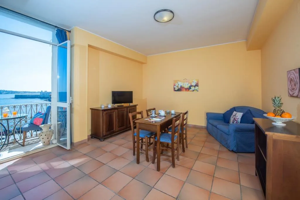 Soggiorno con divano blu, tavolo da pranzo e balcone affacciato sul mare