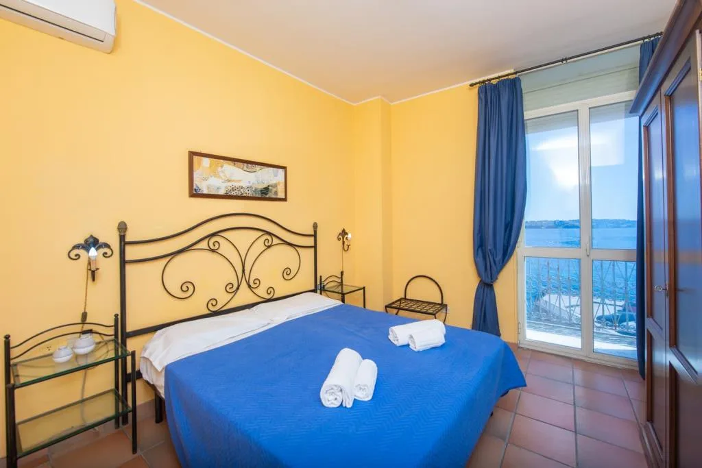 Camera da letto con pareti gialle, letto matrimoniale e vista mare