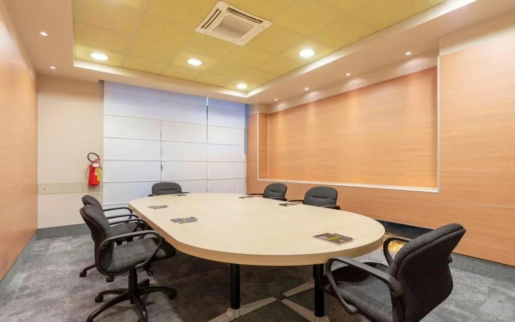 Sala riunioni con tavolo ovale, sedie da ufficio nere e pareti rivestite in legno