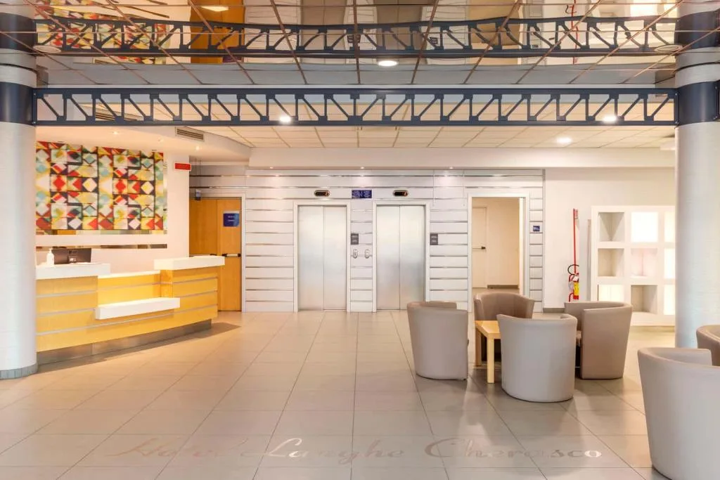 Hall dell'hotel con reception, ascensori, poltrone lounge e decorazione a mosaico colorato