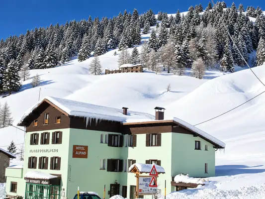 Vista dell'Hotel Alpino circondato da pendii innevati e bosco di abeti coperti di neve