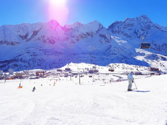 Comprensorio sciistico con sciatori sulle piste innevate e vette alpine sullo sfondo