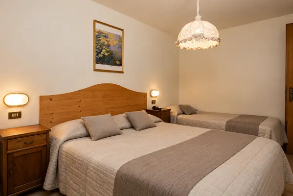 Camera tripla con letto matrimoniale e letto singolo, testiera in legno e comodini