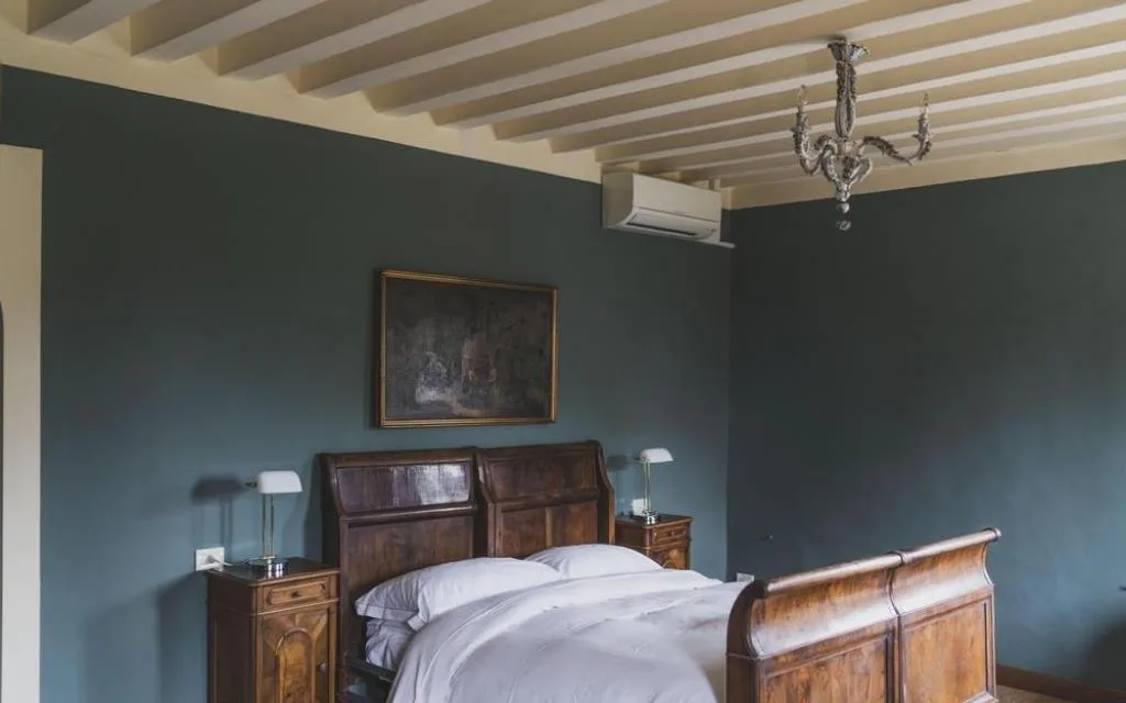 Camera con pareti verdi, letto in legno e lampadario di cristallo con aria condizionata