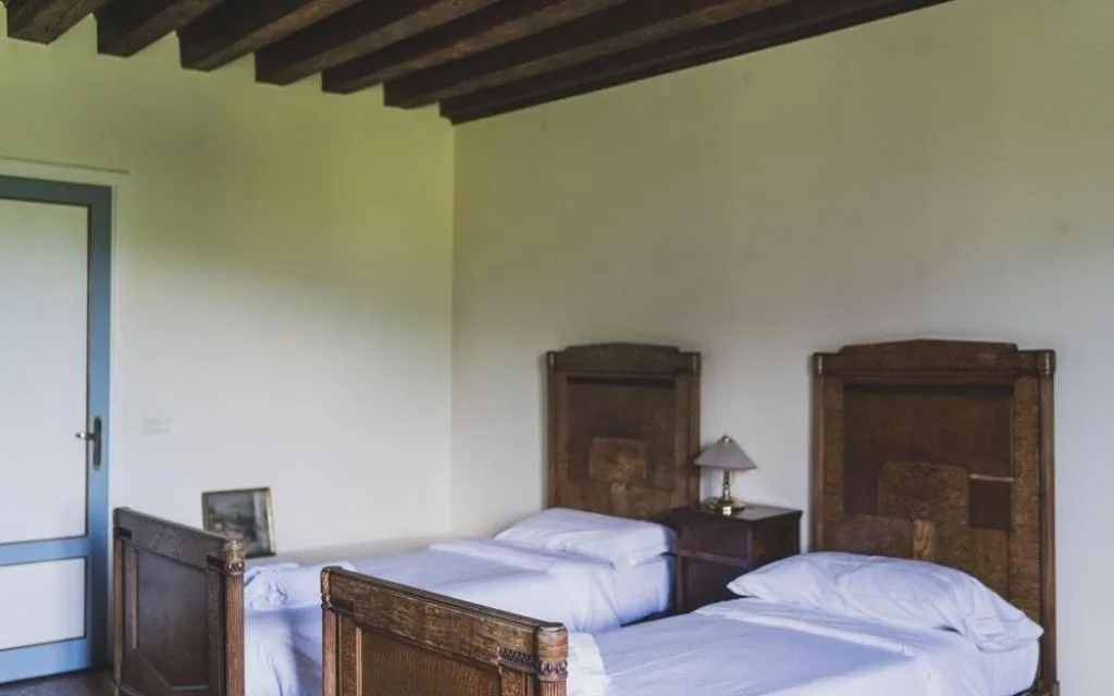 Camera con due letti singoli in legno, travi a vista e testiere decorate