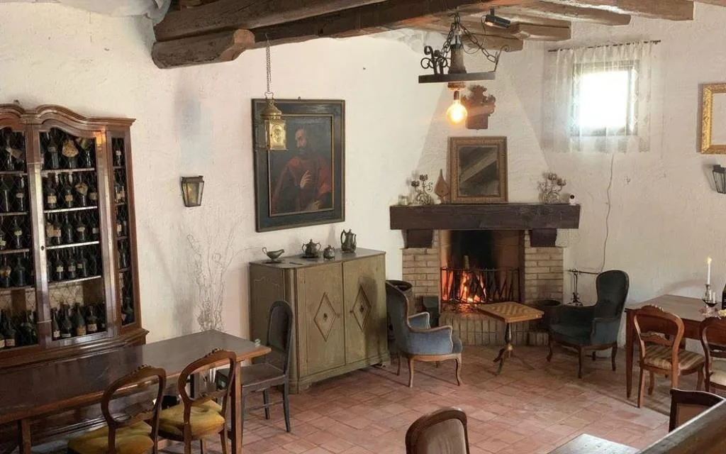 Sala rustica con camino acceso, vetrina di bottiglie di vino e mobili d'epoca