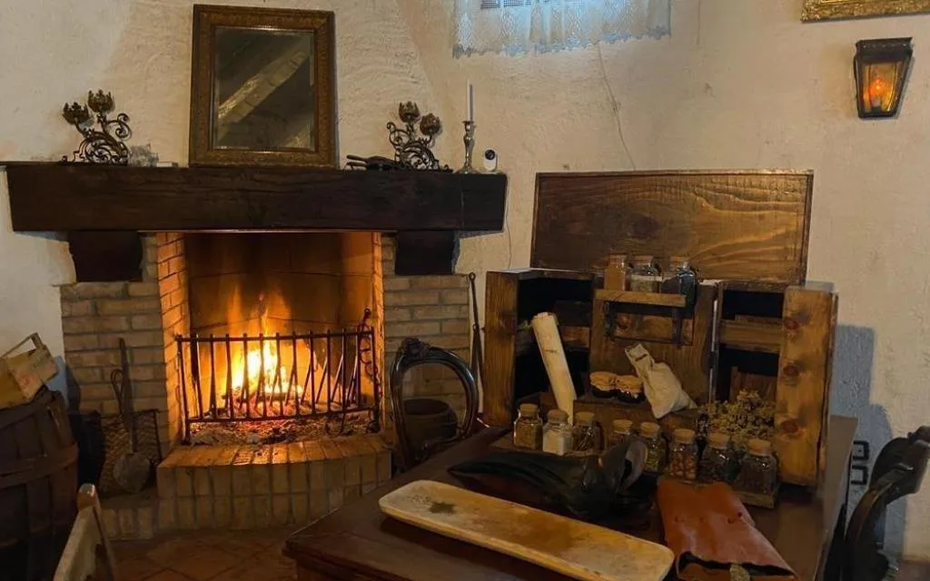 Angolo con camino in mattoni acceso e mobile in legno con spezie ed erbe