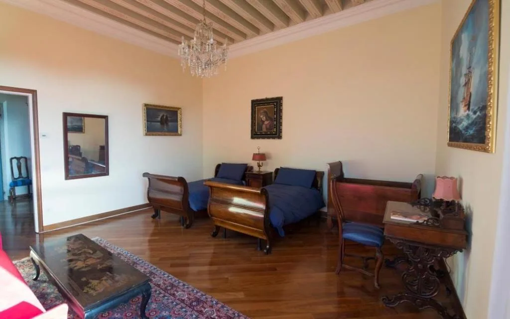 Stanza con due letti in legno, lampadario di cristallo e pavimento in parquet