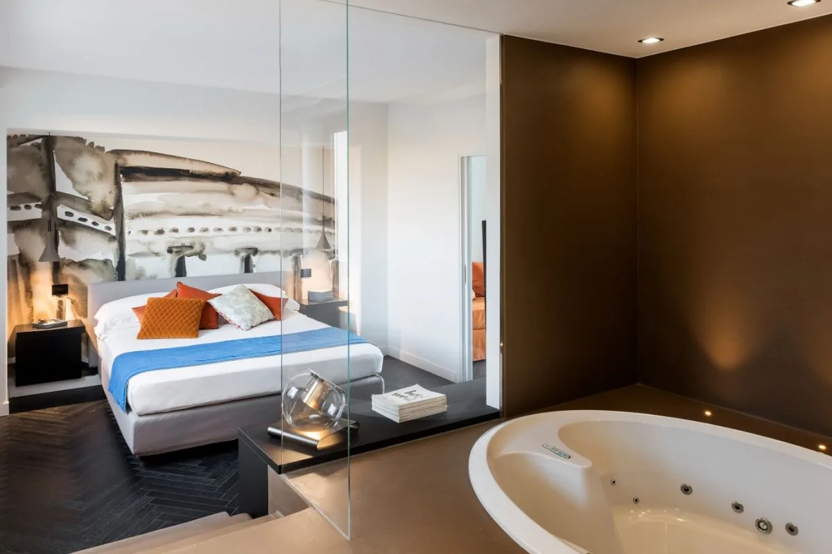 Suite con vasca idromassaggio, parete a vetri e letto con murale artistico