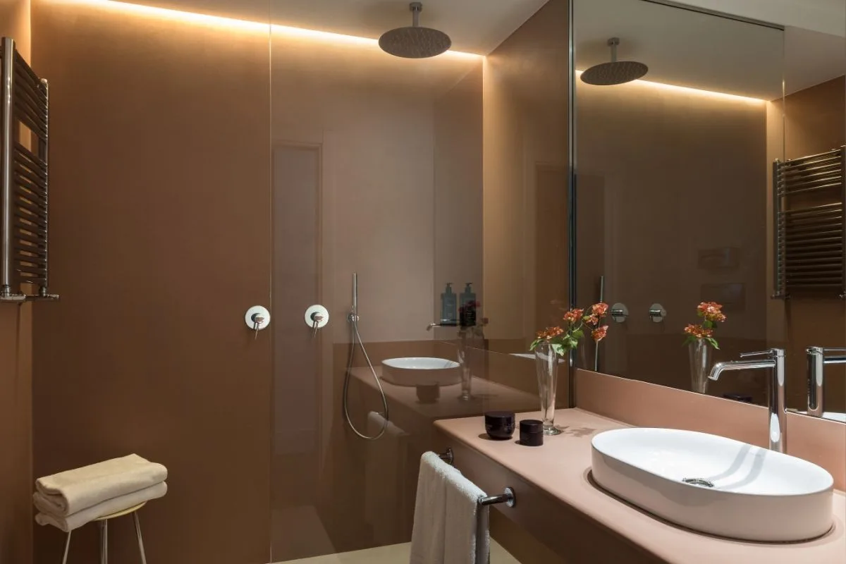 Bagno moderno color cipria con doccia a pioggia, lavabo da appoggio e grande specchio