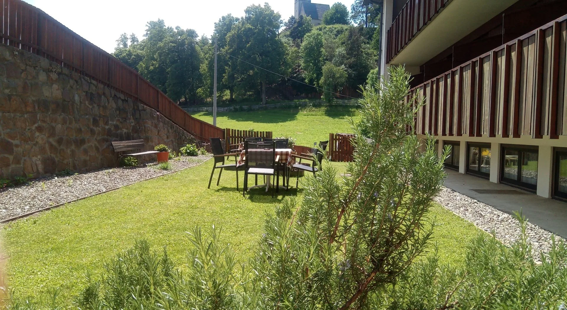 Giardino con tavolo e sedie, prato verde e muro in pietra circondato dal verde