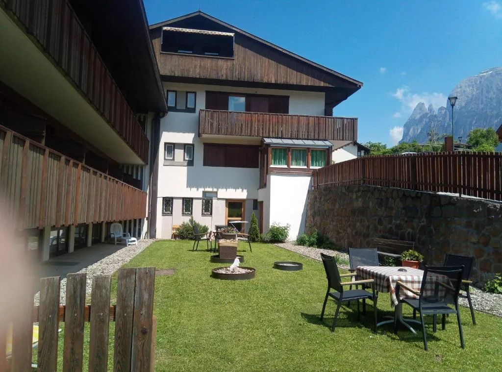 Cortile con giardino, tavoli e sedie e vista sulle Dolomiti in una giornata soleggiata