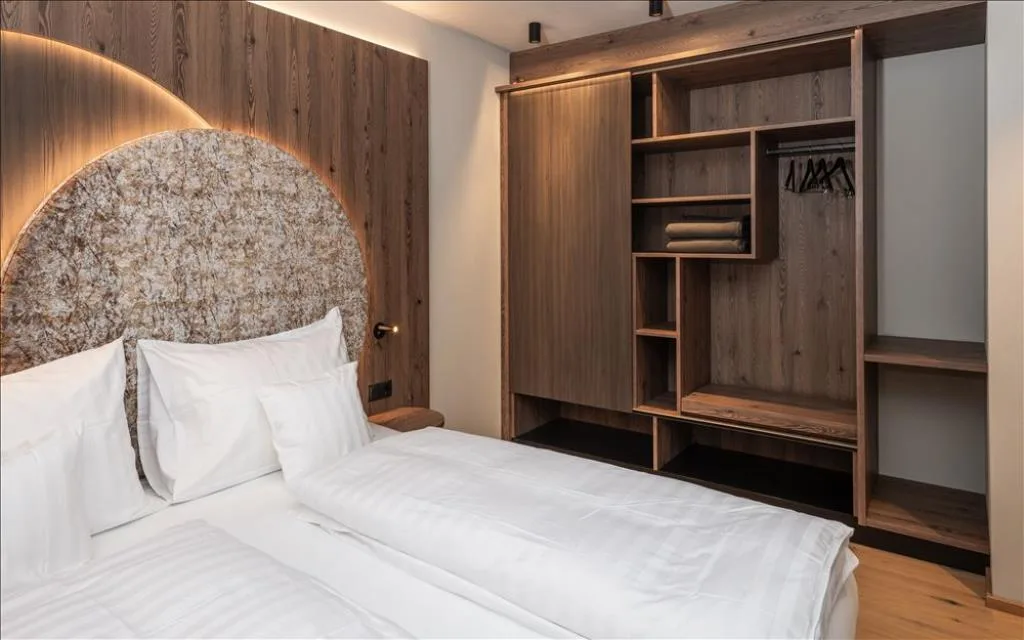 Camera con letto matrimoniale, testiera illuminata e armadio aperto in legno