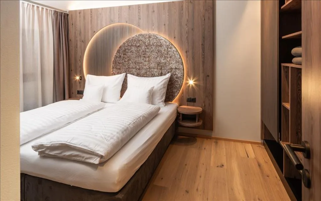 Camera da letto con parete in legno, testiera circolare e pavimento in parquet