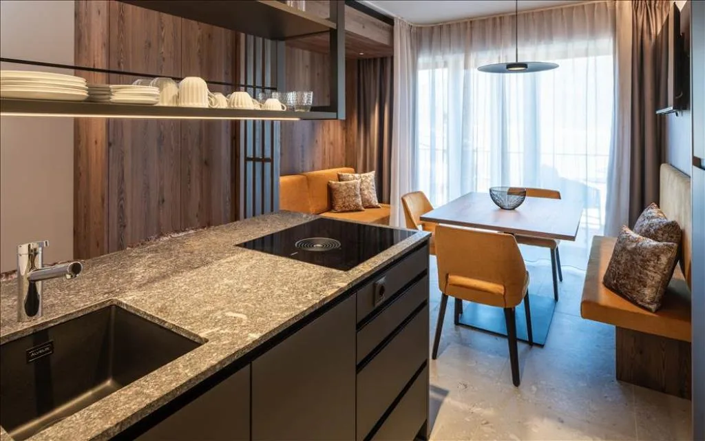 Cucina con piano in granito e lavello accanto alla zona pranzo luminosa