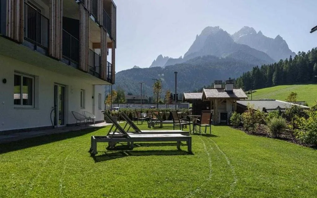 Giardino con lettini prendisole e vista sulle vette delle Dolomiti