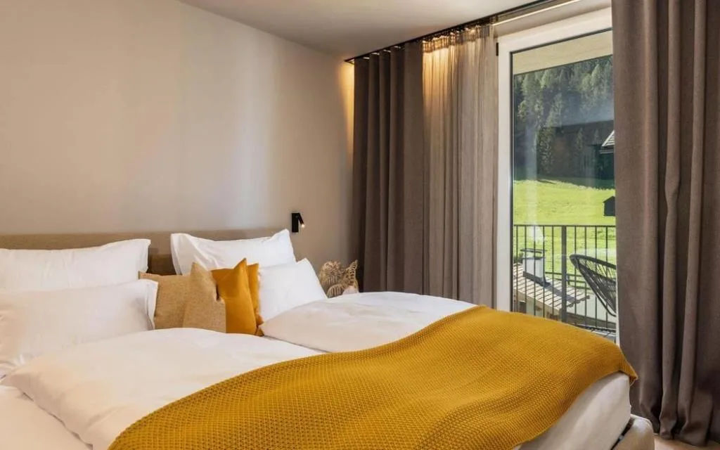 Camera da letto con biancheria bianca e gialla e vista sul prato