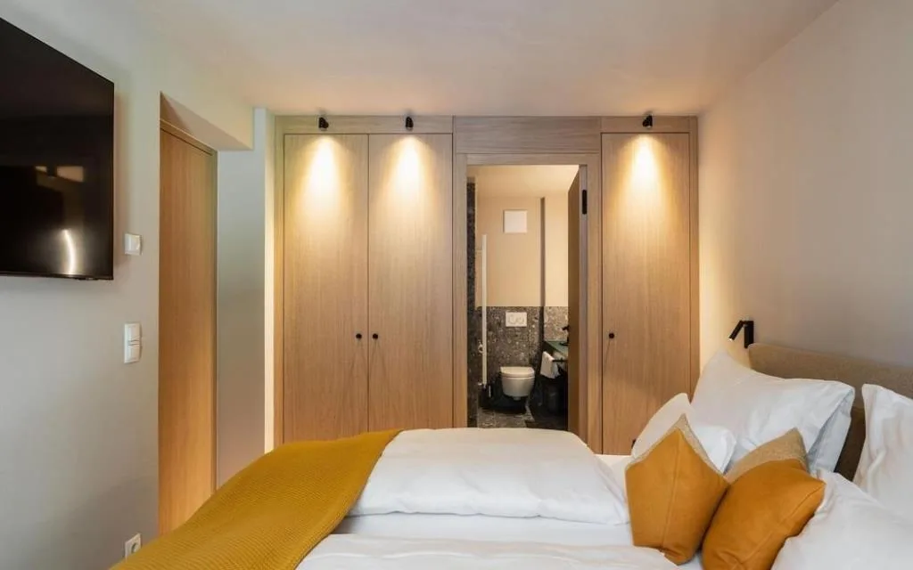 Camera da letto con armadi in legno, TV e bagno adiacente