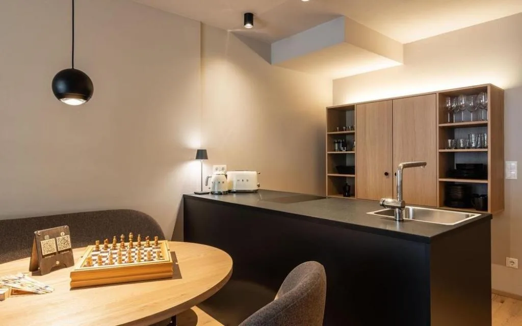 Cucina moderna con isola nera, scaffali in legno e zona pranzo