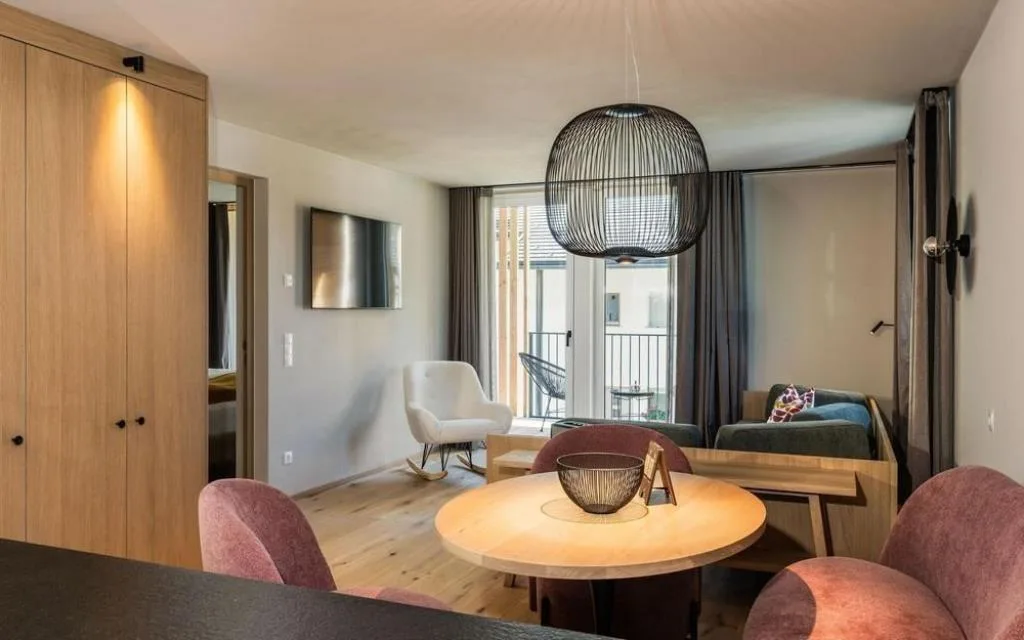 Soggiorno elegante con tavolo tondo, poltrone rosa e grande lampadario