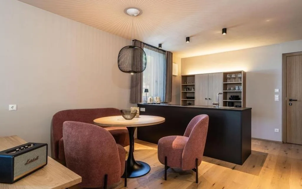 Zona pranzo con poltroncine rosa e cucina attrezzata