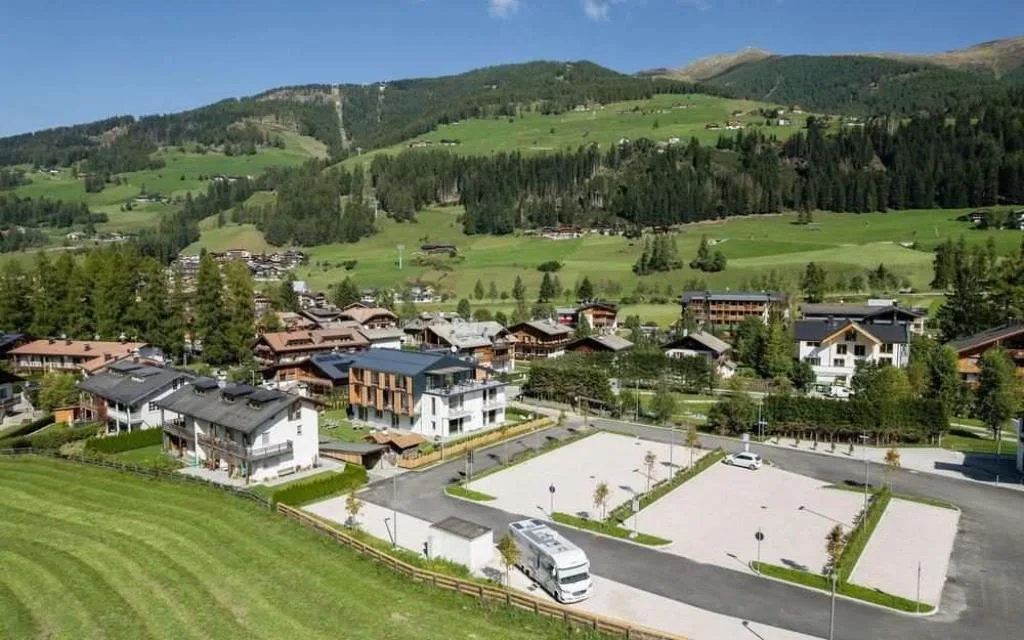 Panoramica aerea della struttura con parcheggio e paesaggio montano