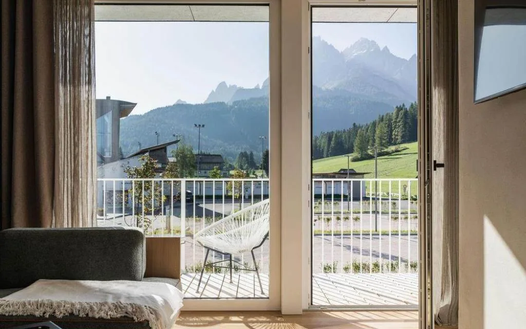 Vista dalla camera attraverso vetrata sulle Dolomiti e il balcone