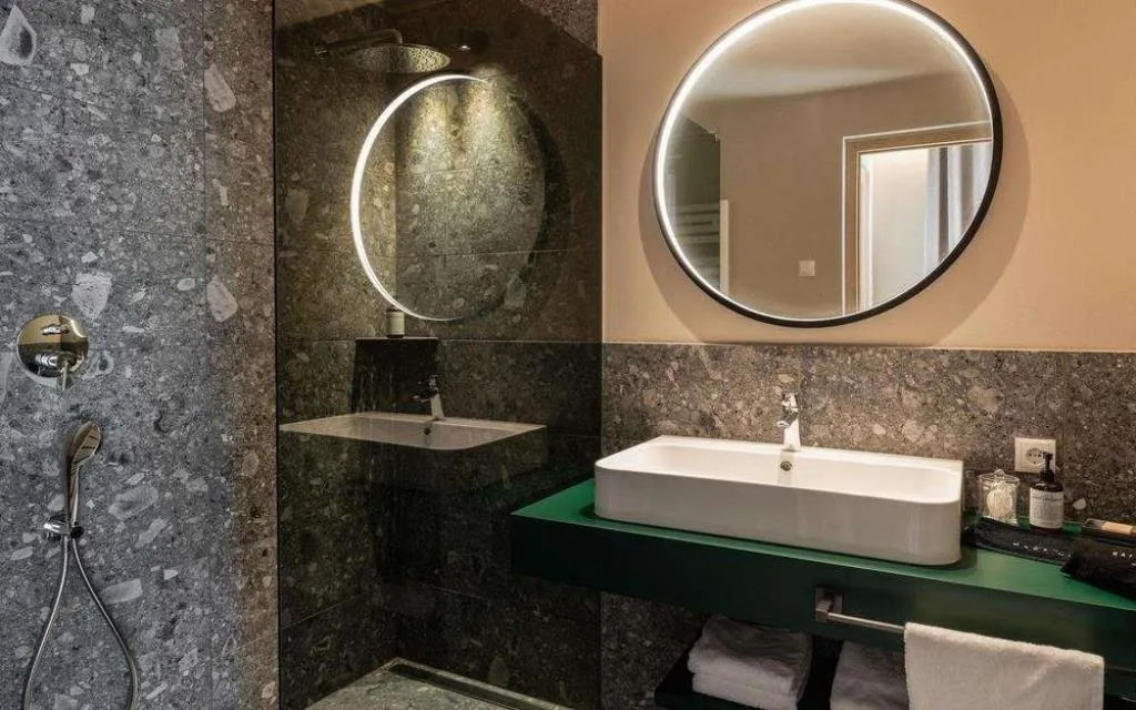Bagno moderno in pietra grigia con doccia e specchio illuminato