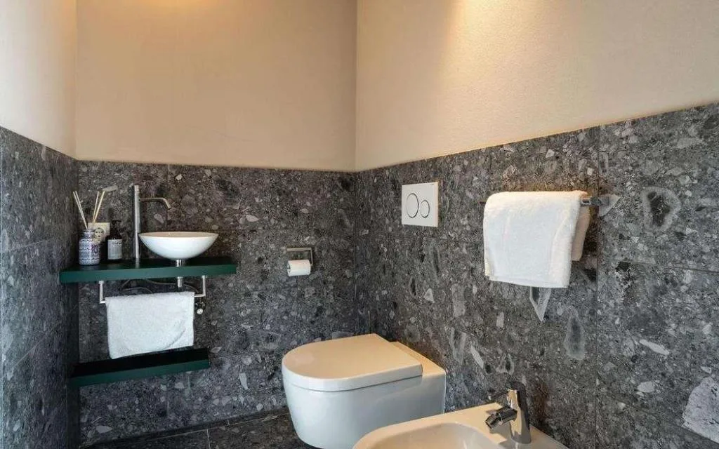 Bagno con rivestimento in pietra, WC, bidet e lavabo
