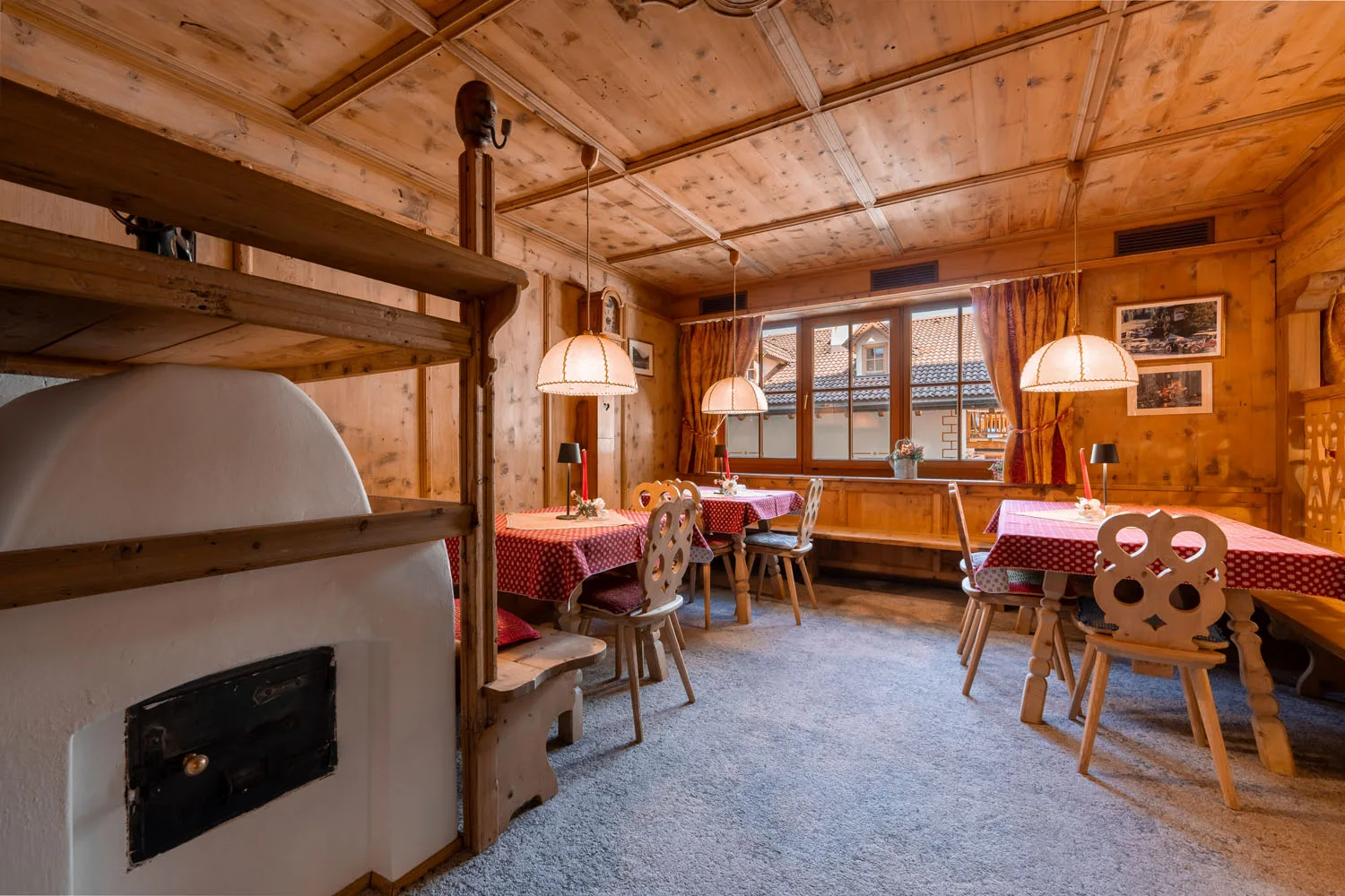Sala ristorante rustica in legno con stufa in maiolica e tavoli apparecchiati