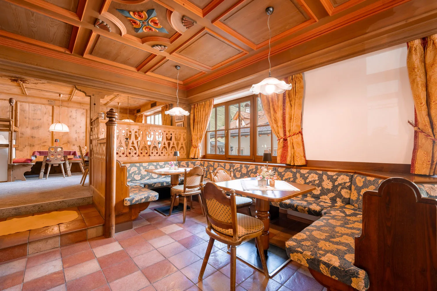 Sala da pranzo rustica con panche imbottite floreali e soffitto in legno decorato