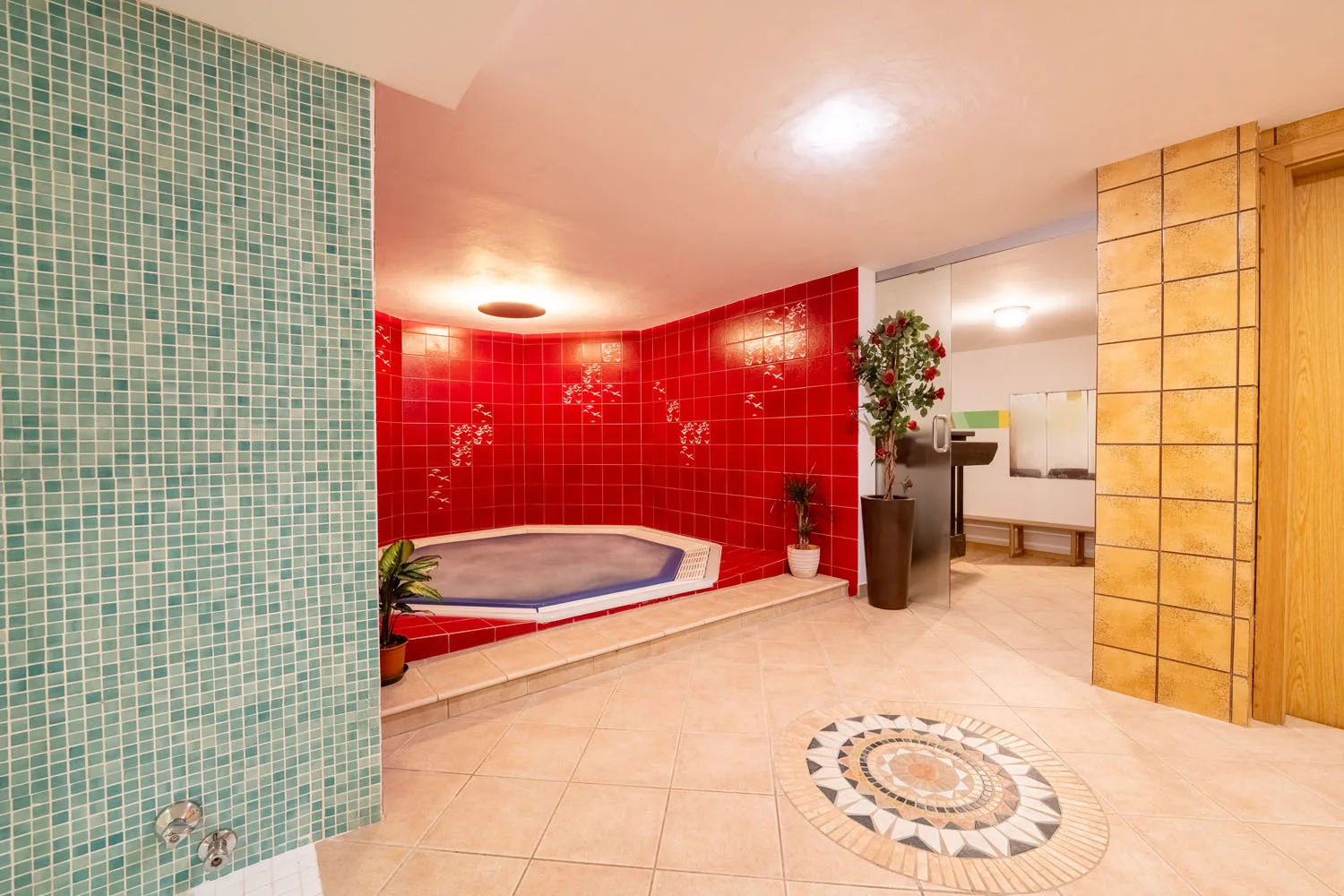 Area benessere con vasca idromassaggio e pareti a mosaico rosso e verde