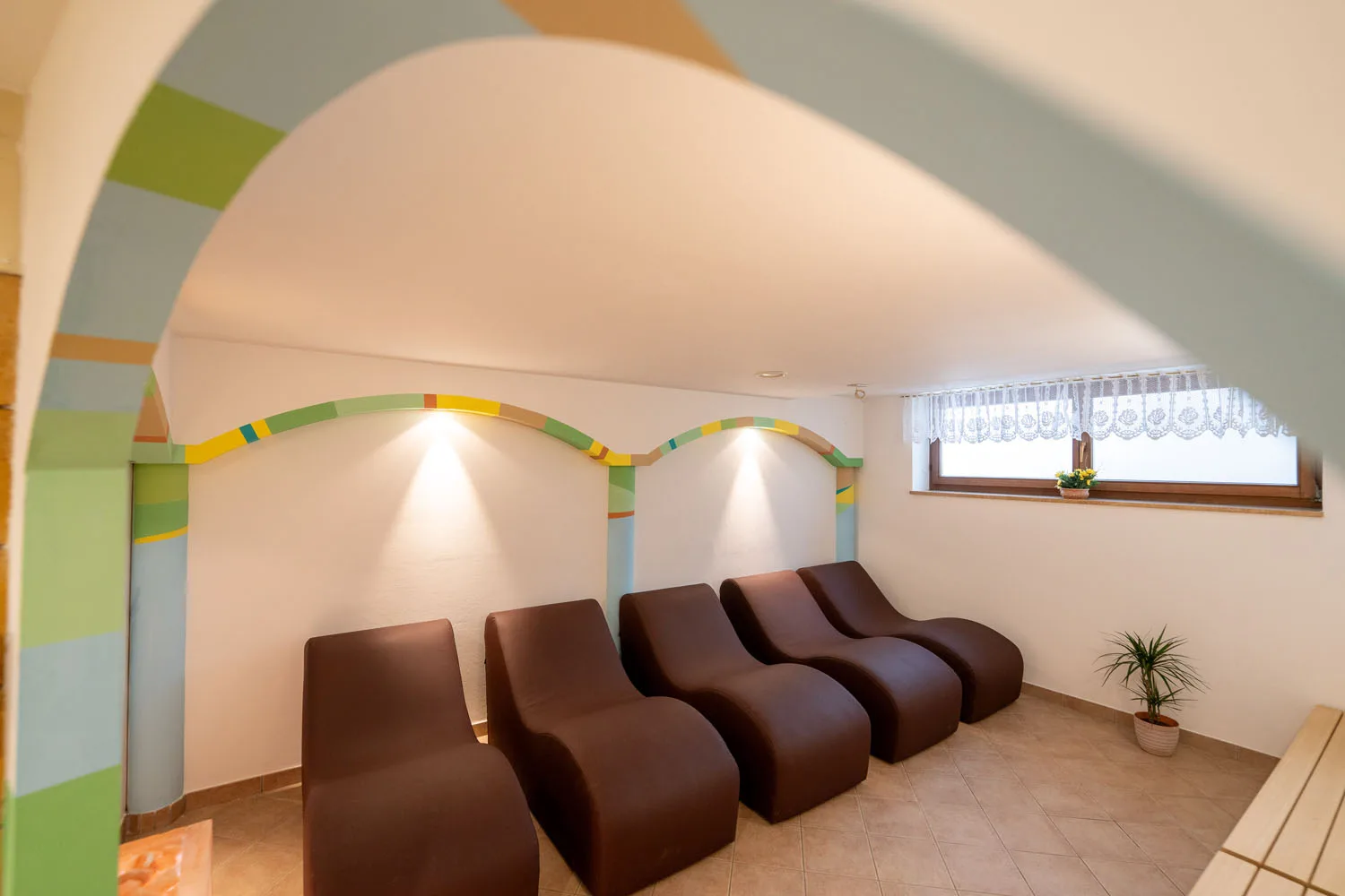 Zona relax della spa con lettini imbottiti marroni e pareti colorate