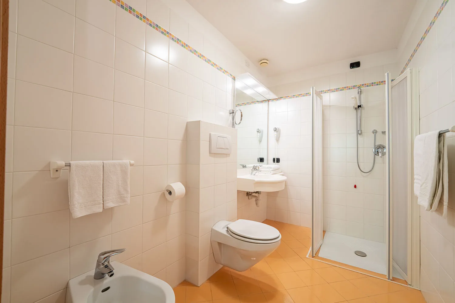 Bagno con doccia, bidet, WC e pavimento arancione