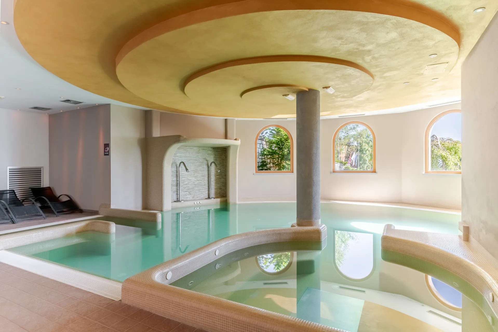 Piscina interna coperta con vasca idromassaggio, soffitto decorato e lettini relax