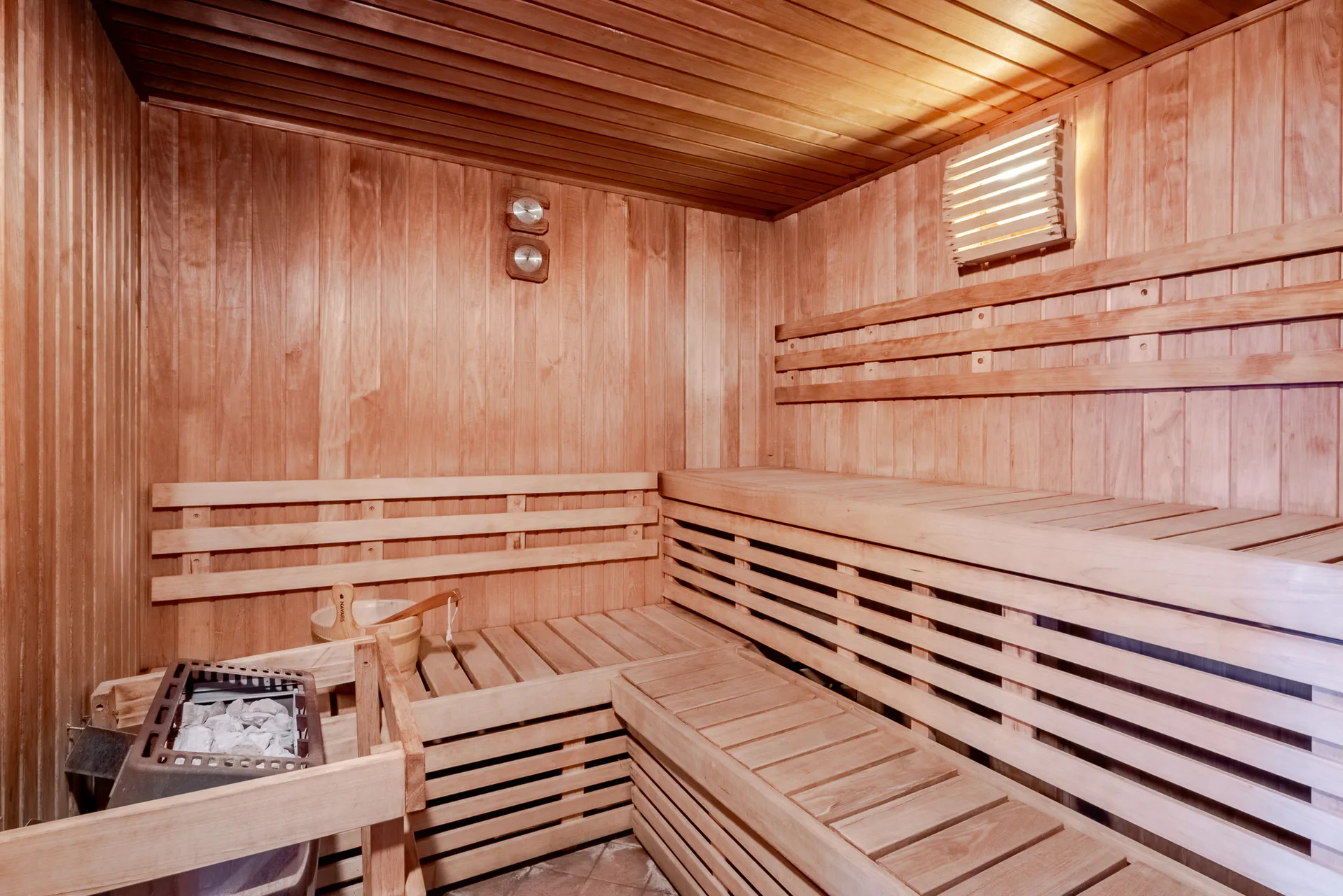 Sauna finlandese in legno con stufa e panche a più livelli