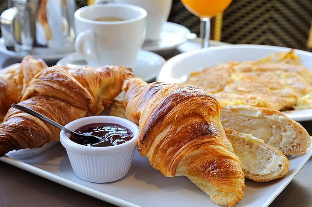 Colazione con croissant, marmellata, caffè e omelette servita su un vassoio