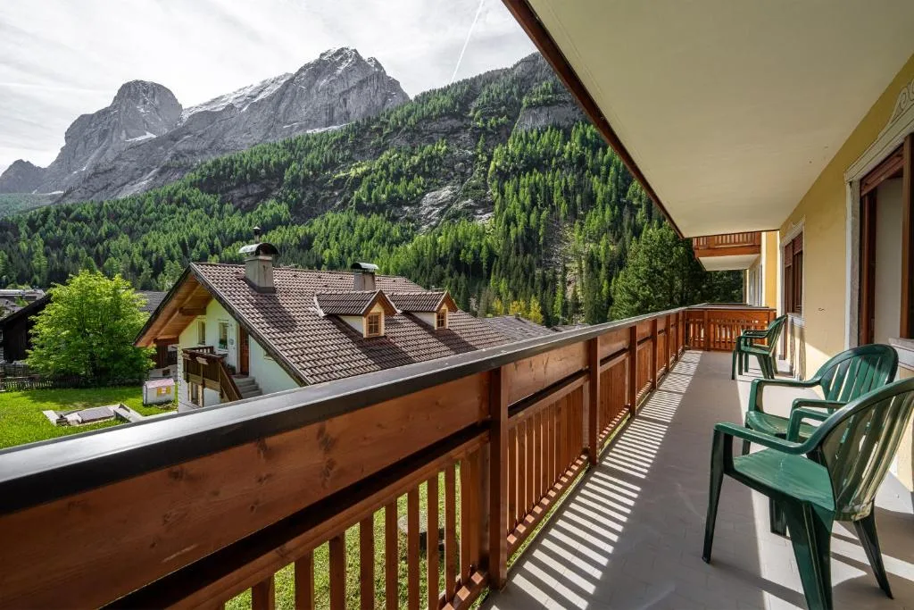 Balcone in legno con sedie affacciato su montagne dolomitiche e boschi