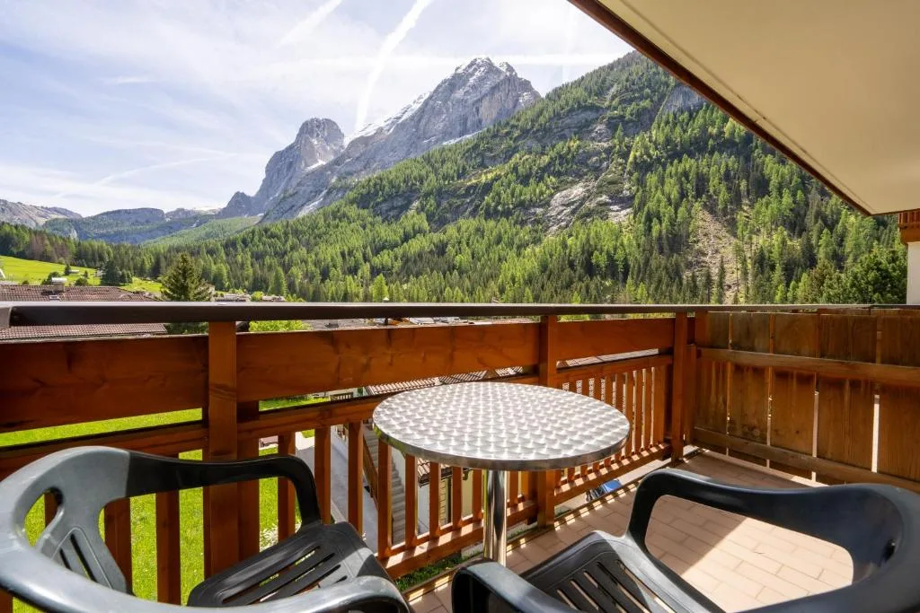 Balcone con tavolino e sedie affacciato su vetta rocciosa e boschi