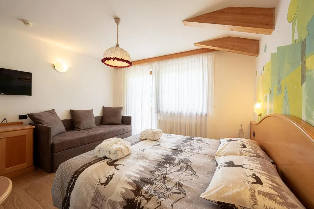 Camera da letto con divano, decorazione murale a tema bosco e travi in legno