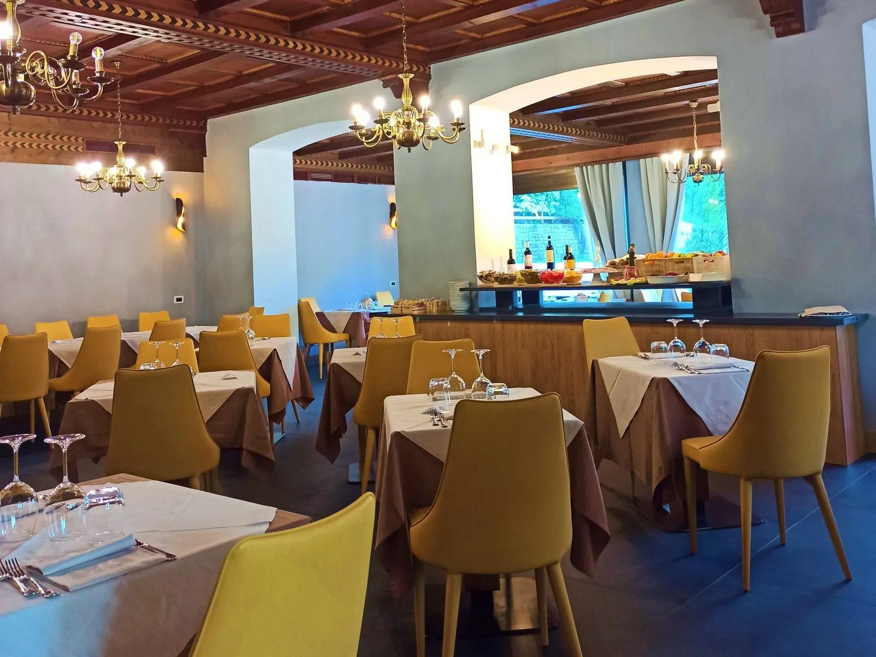 Sala ristorante con buffet, lampadari dorati e soffitto in legno decorato