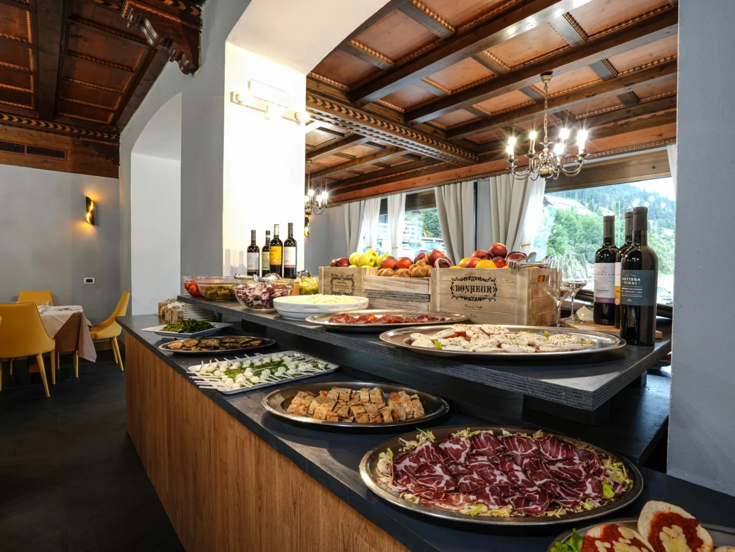 Buffet del ristorante con salumi, formaggi e frutta fresca in cassette di legno