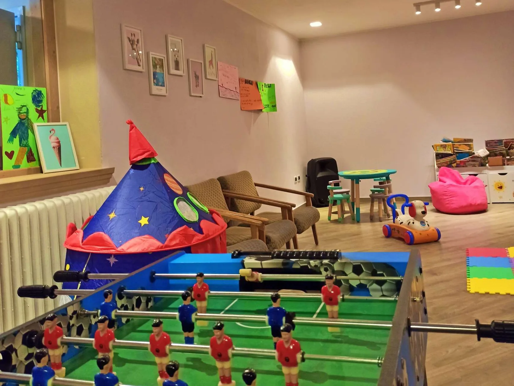 Sala giochi per bambini con calcio balilla, tenda a razzo e area lettura
